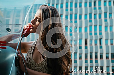 Old communication. Oldfashion town. Vintage concept. Woman with payphone. Oldstyled city. Stock Photo