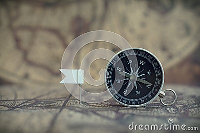 Old compass and flag marking pins on blur vintage map background, journey planning concept Stock Photo