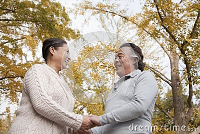 Old couple holding hands and smiling in park Stock Photo