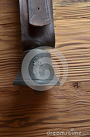 Old cowbell with leather strap on pine wood Stock Photo