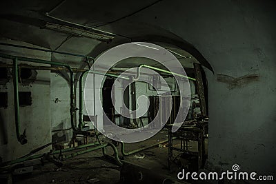 Old creepy basement of abandoned asylum. Old rotten boiler, heating pipes Stock Photo