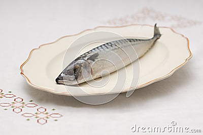 Old decorative presentationdish with tasty raw mackerel fish on table with an embroidered tablecloth Stock Photo