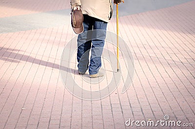 Old depressed man walk alone down the street with walking stick or cane feeling lonely and lost view from back Stock Photo