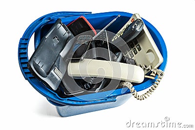Old desk phones, cordless phone, cell phones and smartphones in a trash can Stock Photo