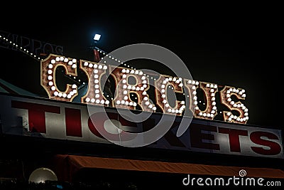 Old dimly lit circus sign with light bulbs in the dark over a ticket stand. Typical view of an entrance to a circus. Concept of Editorial Stock Photo