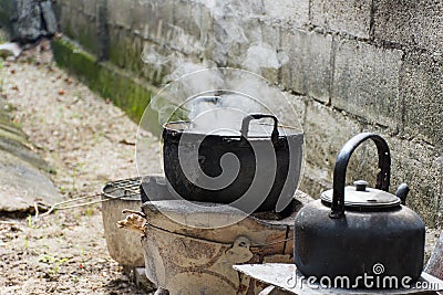 Old dirty cooking pot and bowl boiled water with steam. Stock Photo
