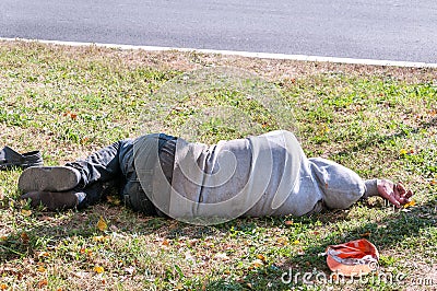Old dirty drunk or drug addict barefoot homeless or refugee man sleeping on the grass in the street social documentary concept Stock Photo