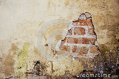 Old dirty and grungy plastered wall facade of an abandoned house with a hole showing the underlying red bricks Stock Photo