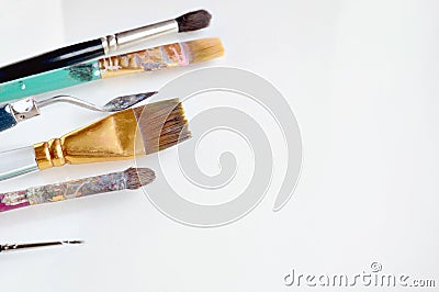 Old dirty painting brushes scattered on a white background. Painting brushes covered in oil paint and varnish. Background for a te Stock Photo