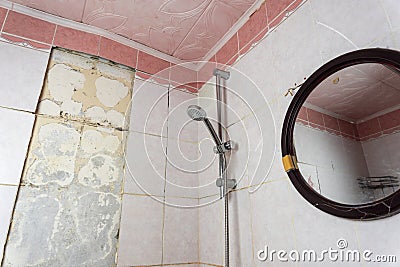 old dirty shabby bathroom with fallen tiles. old shelf. shower stand Stock Photo