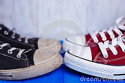 Old dirty shabby and new unworn sneakers close-up on color backg Stock Photo