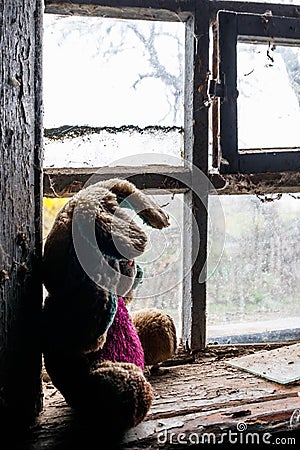 Old dirty stuffed toy rabbit on windowsill in abandoned house Stock Photo