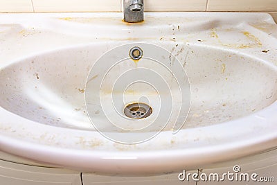Old dirty washbasin with rust stains, limescale and soap stains in the bathroom with a faucet, water tap Stock Photo