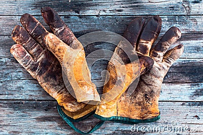 Old and dirty working gloves over wooden table, gloves for each finger Stock Photo