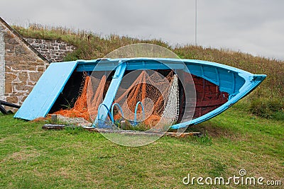 Old disused timber built fishing boat with nets and lobster pots on display Stock Photo