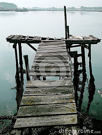 Old dock floating in foggy weather with town showing up in the background Stock Photo