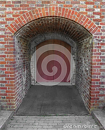 Old door at the end of a brick tunnel. Stock Photo