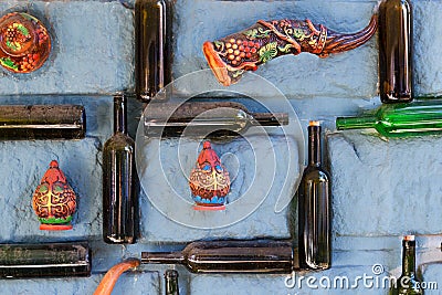 Old dusty empty bottles of wine, vintage decorative elements in Greek style - dishes and horn for drinking are glued on stone wall Stock Photo