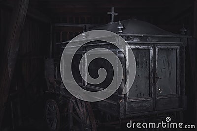 Old and dusty funeral horse carriage or hearse abandoned in a barn Stock Photo