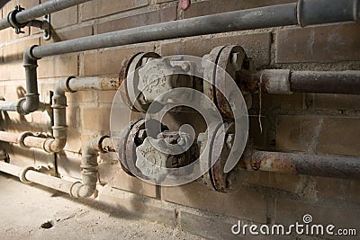 Old dusty open close valve on yellow brick wall Stock Photo