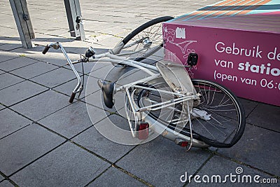 Old Dutch style bicycles lying on the pavement sidewalk with a bent broken back wheel Editorial Stock Photo