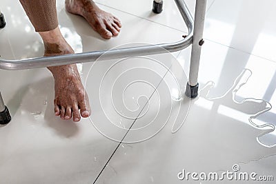 Old elderly people walking on wet areas,water spilled on the floor at home,careful of slippage,asian senior woman stepping on the Stock Photo