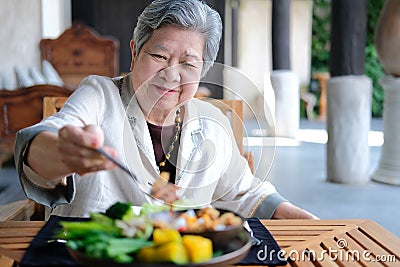 Old elderly senior elder woman eating food. mature retirement lifestyle Stock Photo