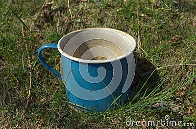 Old enamel metal battered mug grass garden Stock Photo