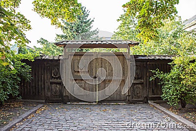 Old entrance gate made of wood with a road of stones or pavers Stock Photo