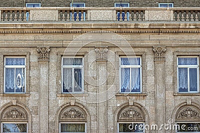 Old exterior stone wall with row of windows with lace curtains Stock Photo