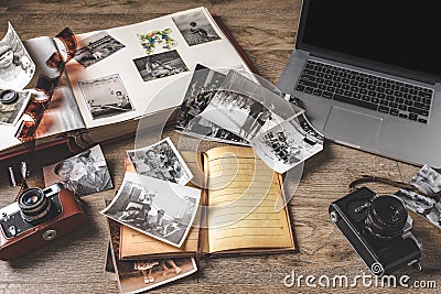 Old family photos and album on wooden background. Vintage pictures, camera, notepad and modern notebook Stock Photo