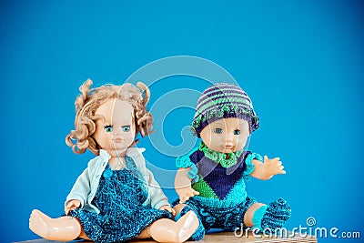 Old-Fashioned baby Doll dressed in knitted costume sits on shelf on blue background Stock Photo