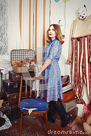 Old fashioned girl standing still near chair Stock Photo