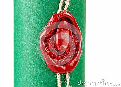 Old fashioned medieval red wax seal imprinted with an ornate design secures a string around a tightly rolled scroll with vibrant Stock Photo
