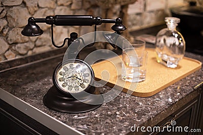 Old fashioned retro dark brown metal telephone with clear glasses on marble table Stock Photo