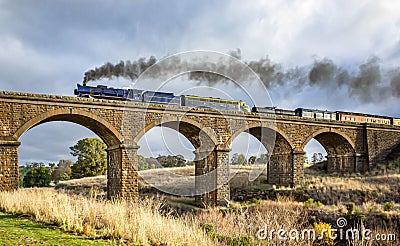 Old Fashioned Steam Train Crossing a Historic Bluestone Masonry Bridge, Malmsbury, Victoria, Australia, June 2019 Editorial Stock Photo