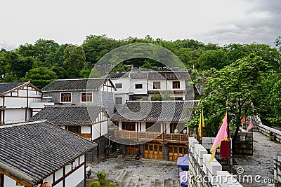 Old-fashioned tile-roofed houses outside stone wall in cloudy sp Stock Photo