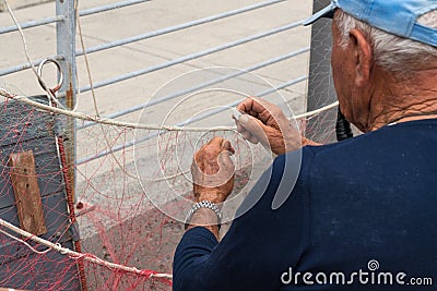 Old fisherman reparing fishing net Editorial Stock Photo