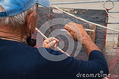Senior fisherman is fixing a fishing net Stock Photo