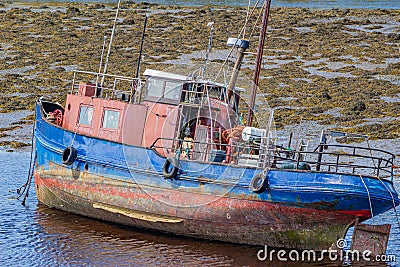 Old fishing boat in Clifden Bay at low tide Stock Photo