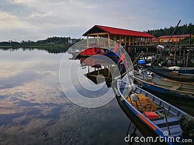 Old fishing boat near wooden jetty. Beautiful malaysian landscape. Sunset reflection in the water. Editorial Stock Photo