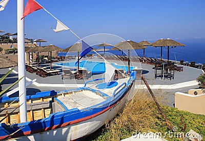 old fishing boat, sun beds and pool on terrace over Mediterranean sea, Santorini Editorial Stock Photo