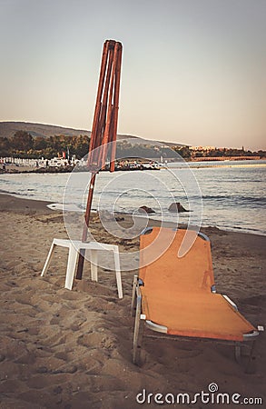 Old folding beach lounge and a wooden umbrella frame on a sandy shore Stock Photo