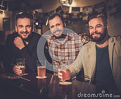 Old friends drinking draft beer at bar counter in pub. Stock Photo