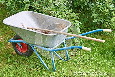 Old garden iron cart in the garden on a green lawn with a shovel Stock Photo