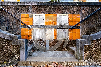 Old gas meter boxes with wooden door on a typical Portuguese wall with azulejos tiles next to stone steps Stock Photo