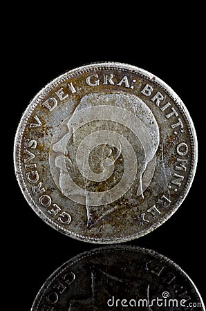 Old George V English coin exposed on black reflecting glass, found in life dig by metal detector.England Stock Photo