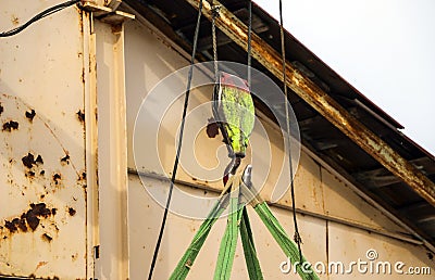 Old girder crane with large iron hook lifts heavy load on slings Stock Photo