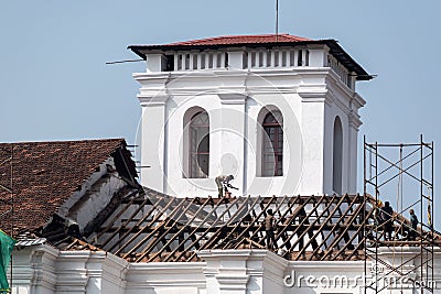 Workers fixing the tiled roof of the ancient Portuguese era Church of St. Francis of Assisi in Old Editorial Stock Photo