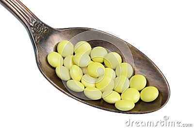 In the old golden spoon there is a small heap pills with valerian to calm the nerves isolated macro Stock Photo